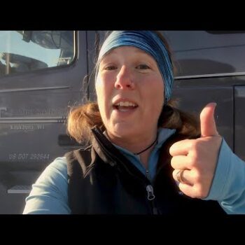 Female truck driver gives a thumbs up in front of Midwest Carriers truck