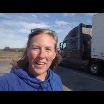 Female truck driver smiling and standing in front of a Midwest Carriers truck