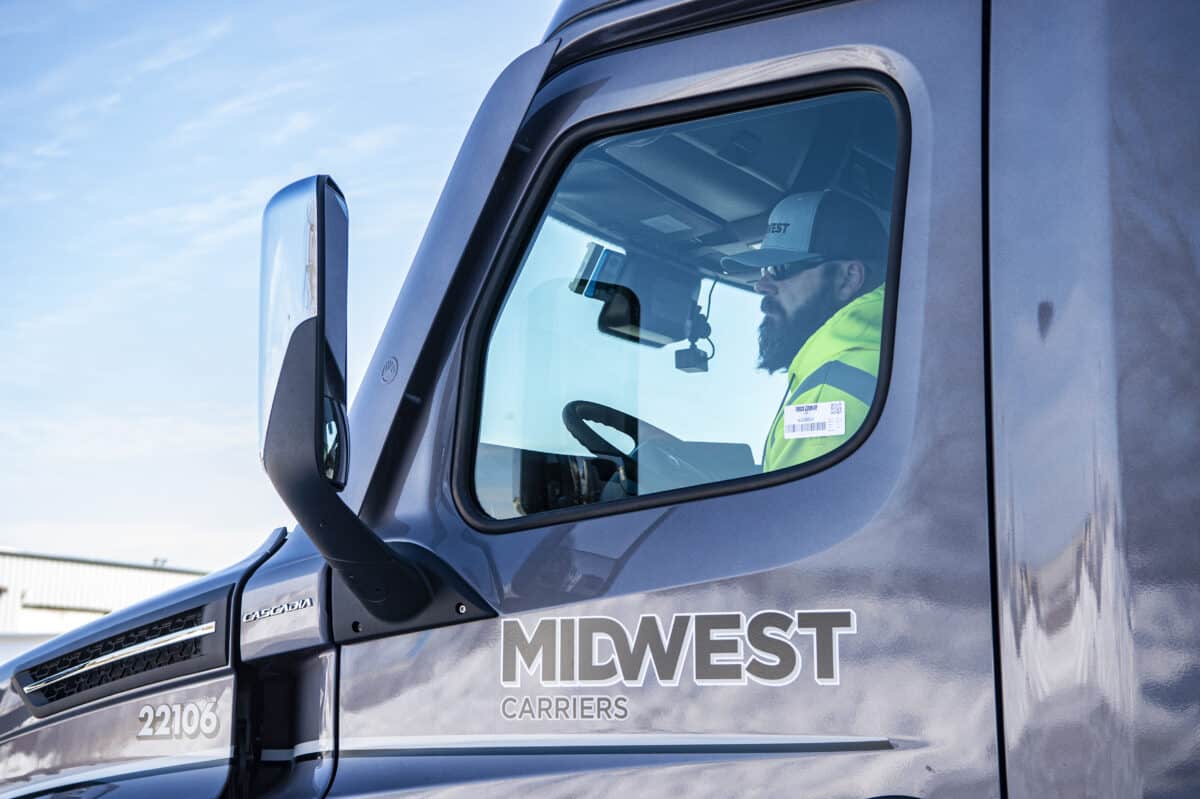 Male truck driver sitting in cab of Midwest Carriers truck