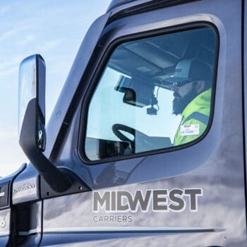 Male truck driver sitting in cab of Midwest Carriers truck