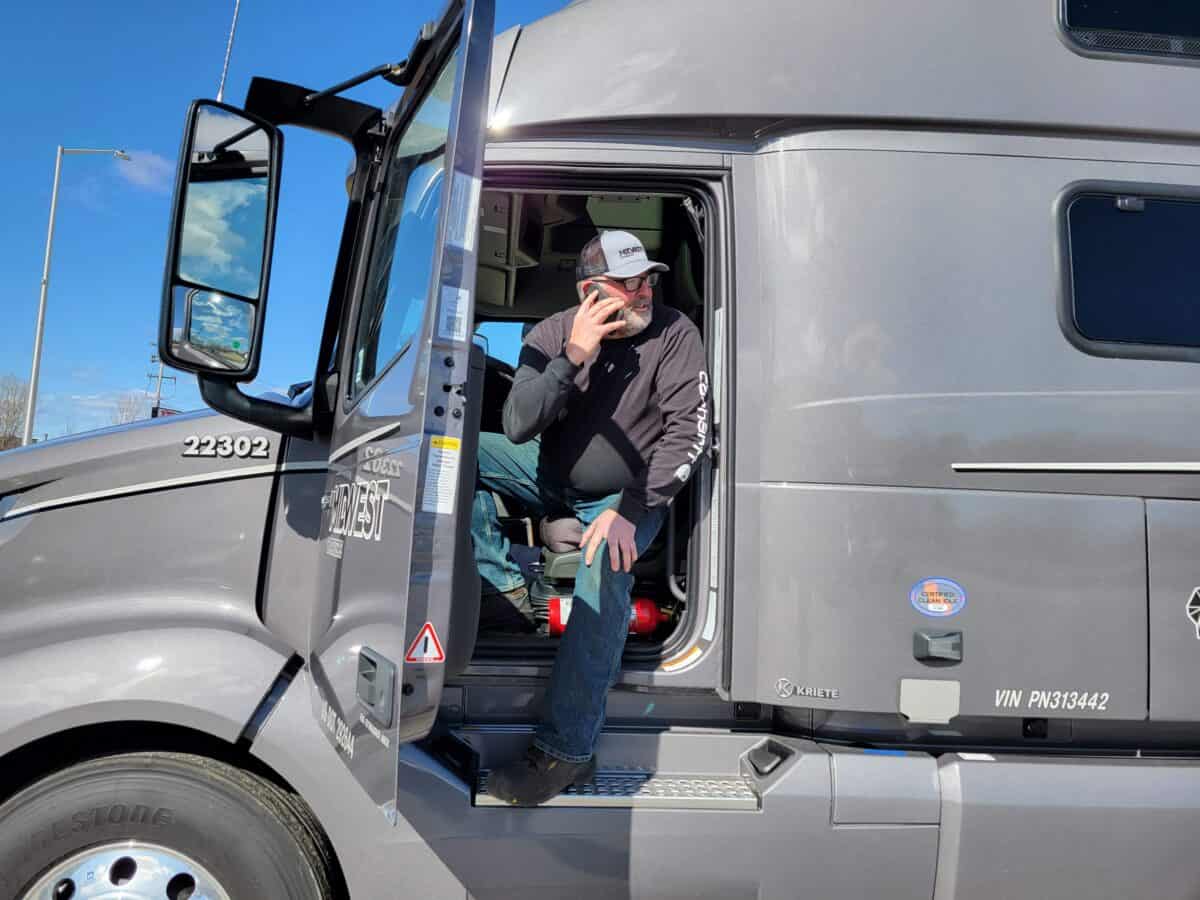 Midwest Carriers truck drivers sits in cab with door open and talking on his phone
