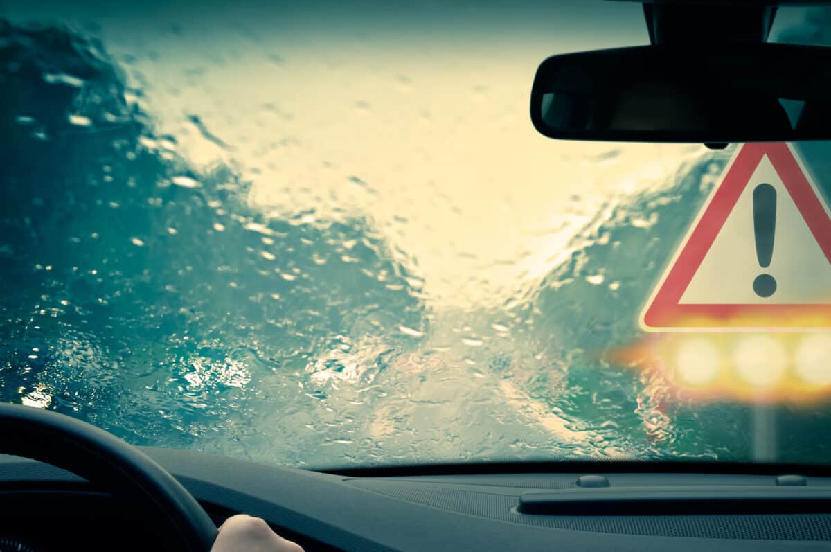 Front view window of car with caution sign visible during bad weather