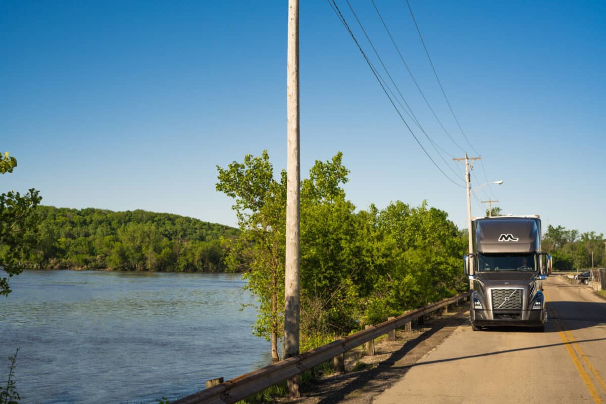 Midwest Truck Drives Along Road with Lake to the Left