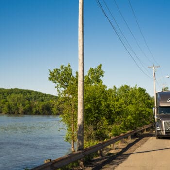 Midwest Truck Drives Along Road with Lake to the Left