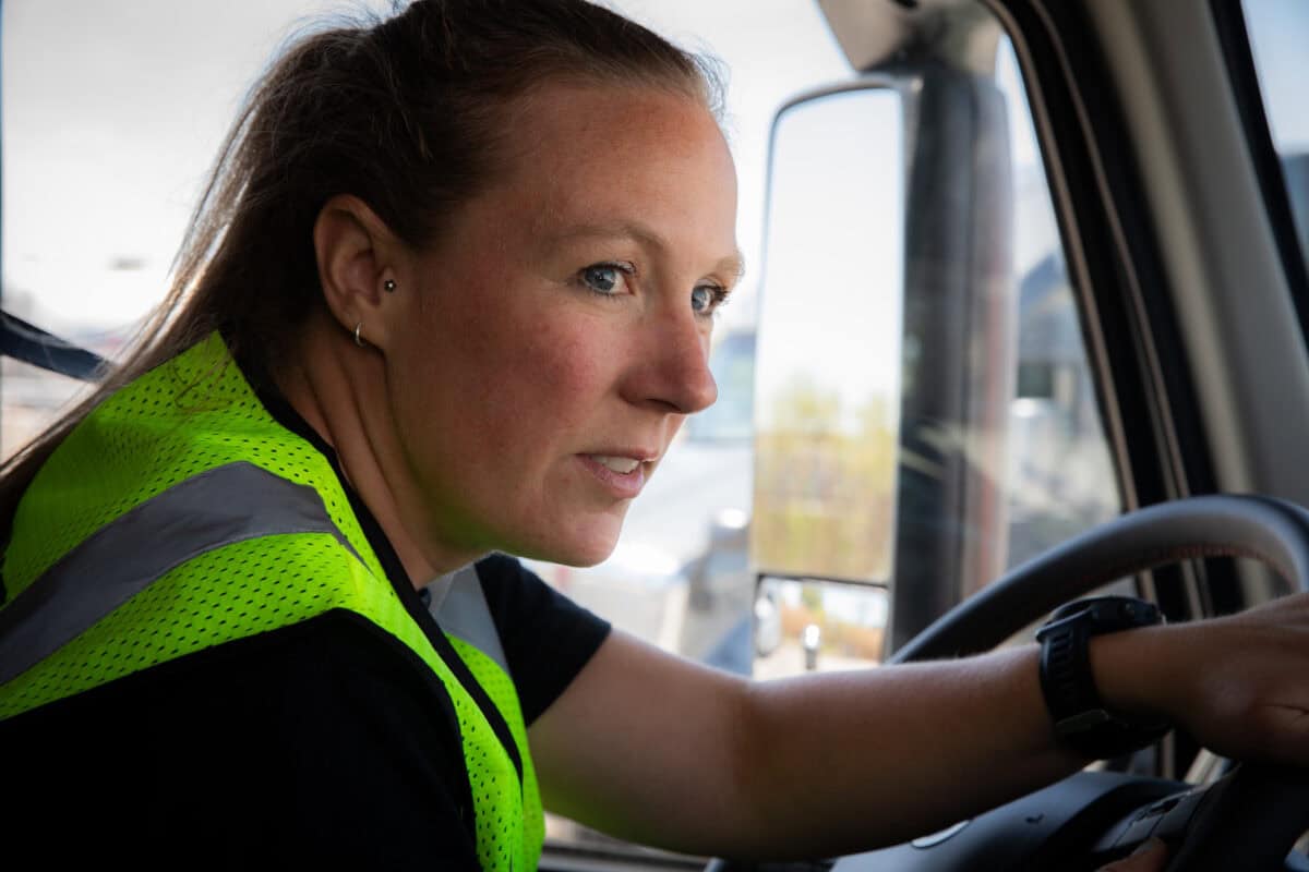 female semi truck driver checking mirrors during turn